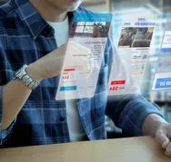 Mann in Freizeitkleidung bei der Interaktion mit einem futuristischen virtuellen Bildschirm einer Anwendung zur Hotelreservierung und Reiseplanung
