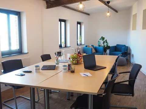 Kleiner Konferenzraum bei e-pixler mit einem Tisch, Stühlen und Sofas.