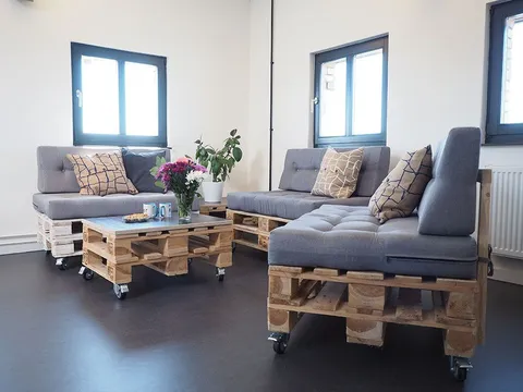 Moderner Lounge-Bereich mit Palettenmöbeln, grauen Polstern und dekorativen Pflanzen.