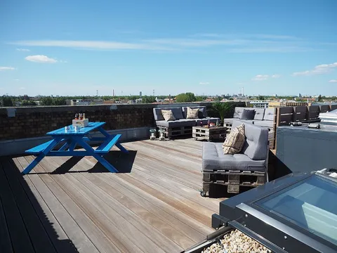 Dachterrasse bei e-pixler mit Sitzgelegenheiten und einem blauen Tisch.