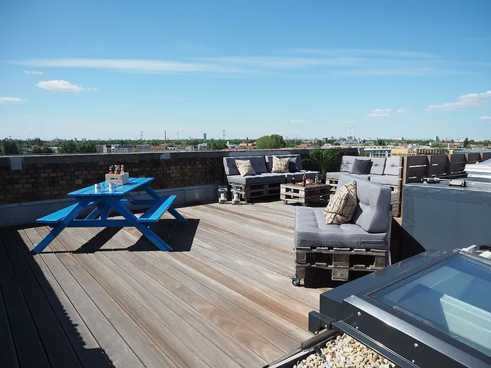Dachterrasse bei e-pixler mit Sitzgelegenheiten und einem blauen Tisch.