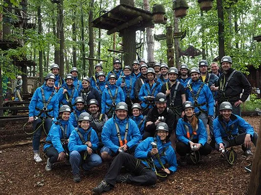 Team von e-pixler beim Sommerfest im Kletterpark, alle in blauen Jacken und Helmen.